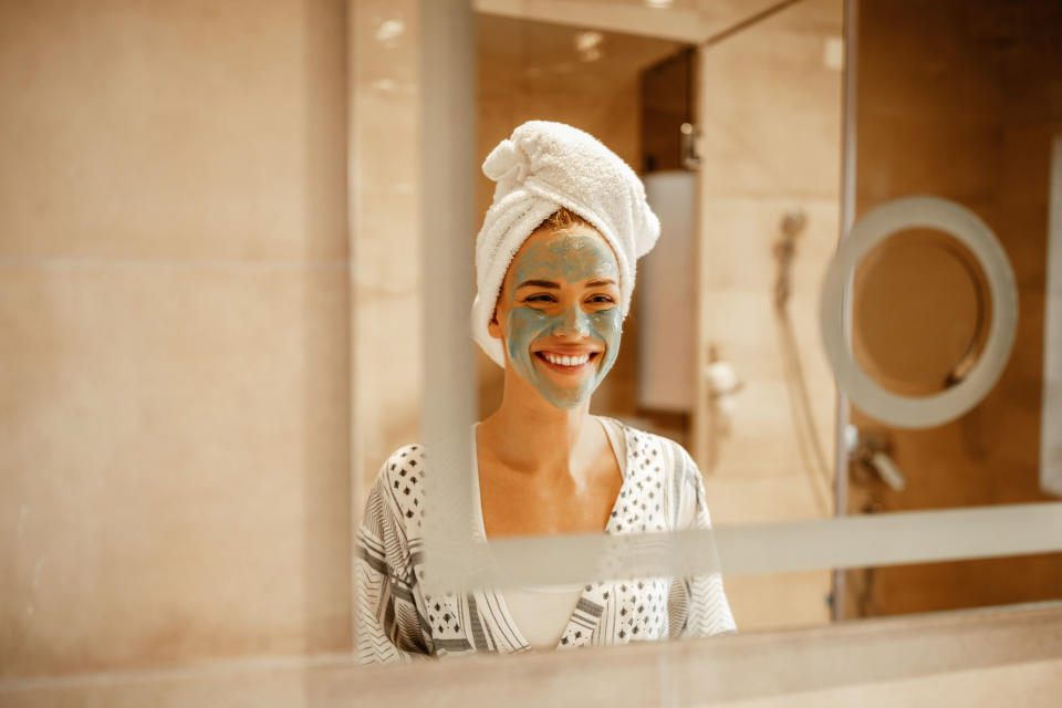 Attractive young woman standing in the bathroom with a facial mask