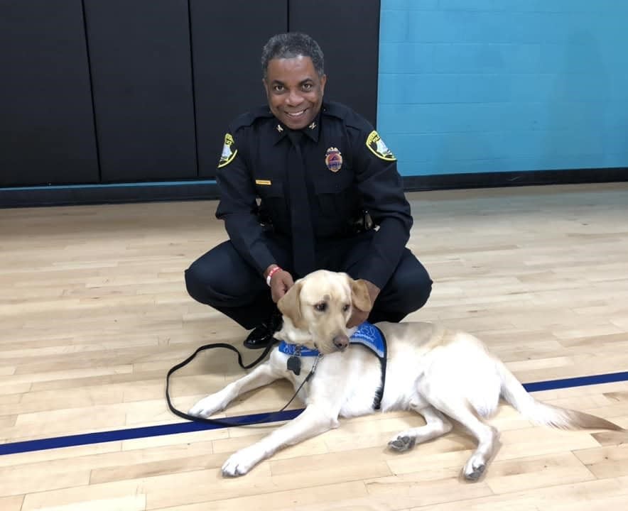 Petersburg Chief of Police Travis Christian poses with a service dog trained by Canine Companions at Petersburg Family YMCA on Friday, December, 1.