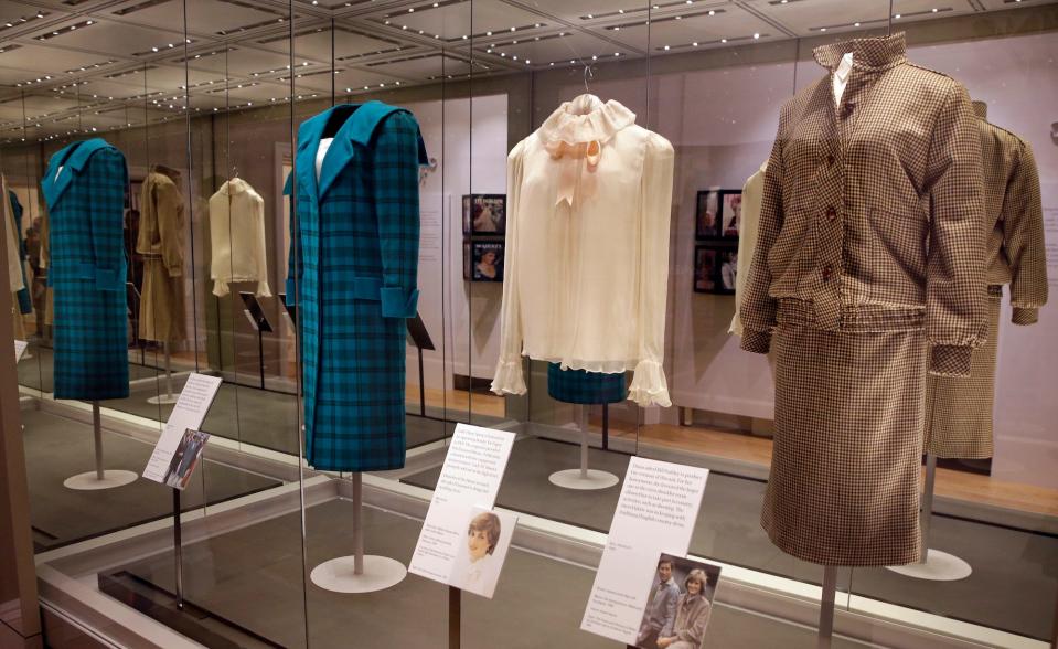 A photo of three of Princess Diana's outfits in a glass case at a museum.