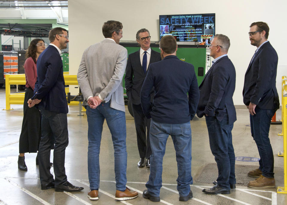 In this photo provided by the California Governor's Office, Gov. Gavin Newsom, center, talks to MOXION employees Thursday, May 25, 2023, in Richmond, Calif. Newsom toured the battery manufacturing plant and touted his updated plan to ease the permitting process for new clean energy projects. (Sheila Fitzgerald/California Governor's Office via AP)