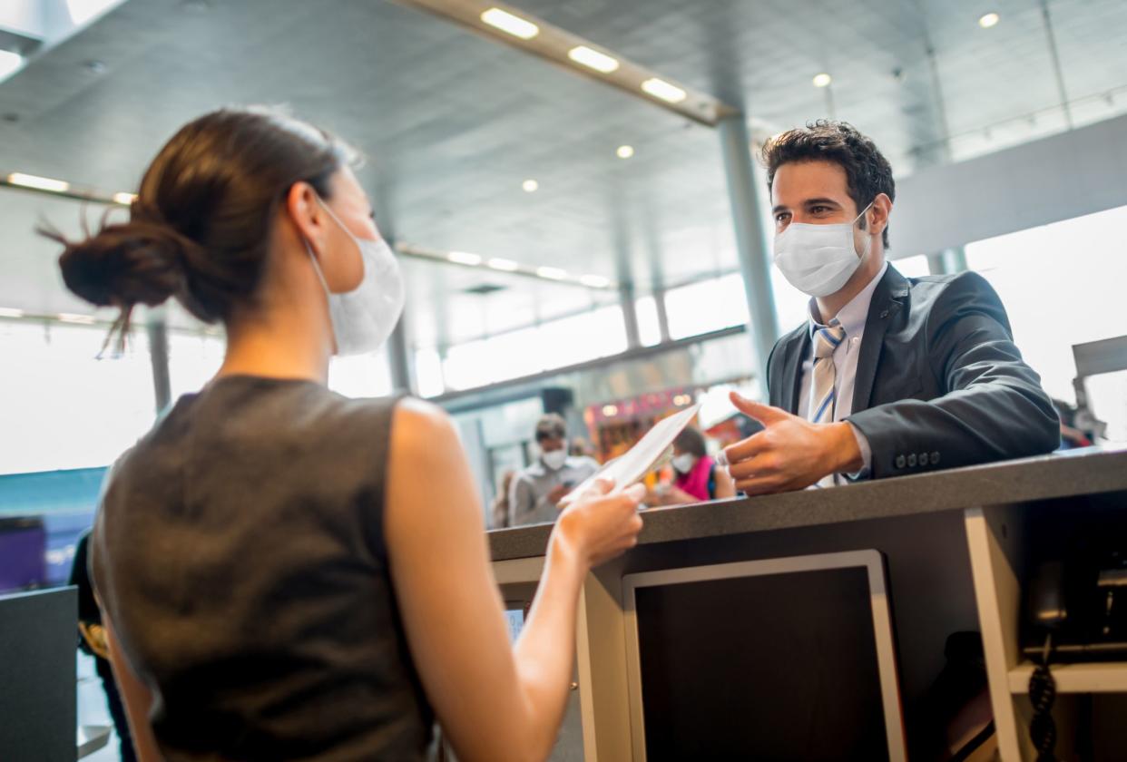 Portrait of a traveling business man doing the check-in at the airport wearing a facemask during the COVID-19 pandemic â€“ travel concepts