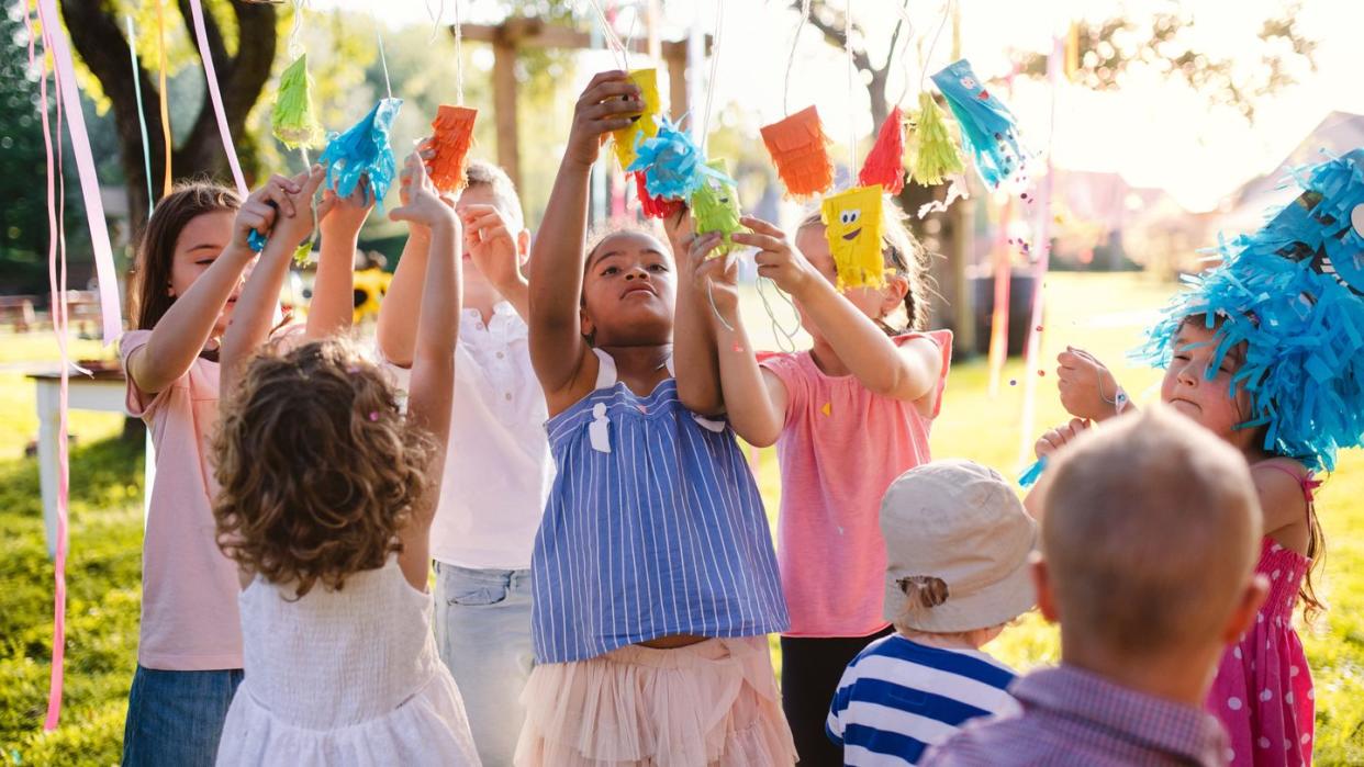 kids hanging up decorated party cups in the backyard