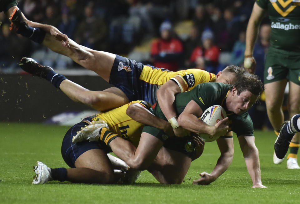 Australia's Jake Trbojevic, foreground, is tackled by Scotland's Luke Bain, top, and teammate during the Rugby League World Cup match between Australia and Scotland at Coventry Building Society Arena, Coventry, England, Friday, Oct. 21, 2022. (AP Photo/Rui Vieira)
