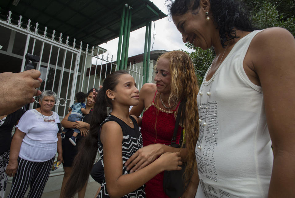Laura Gil, center, stands with her mother Lisset Diaz Vallejo, center, outside the the notary office after her mother married her partner Liusba Grajales, right, in Santa Clara, Cuba, Friday, Oct. 21, 2022. The couple, which has been together for seven years, said they considered marriage a way to also protect their children if something were to ever happen to them. The new Family Code opened up everything from equal marriage to surrogate mothers. (AP Photo/Ismael Francisco)