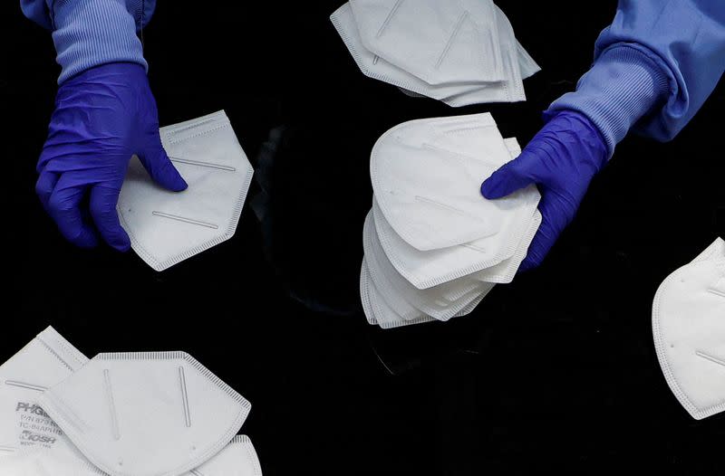 A workers inspects an N95 respirator during manufacturing at Protective Health Gear (PHG) in Paterson, New Jersey