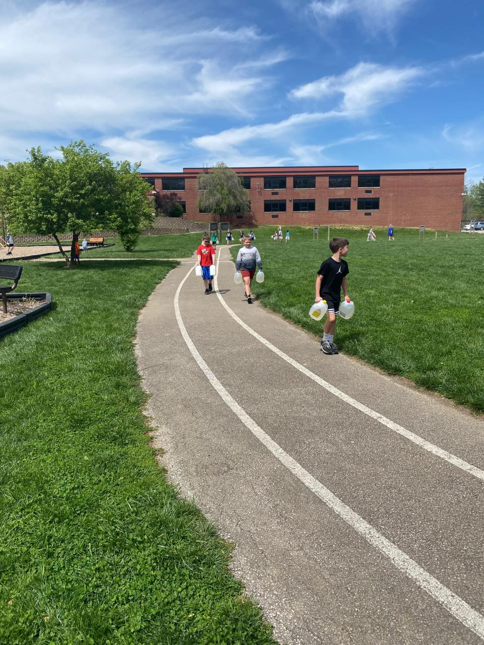 Unionville Elementary School third graders carry jugs of water from the school's pond around the track to simulate the experience of girls in Burkina Faso, Africa.