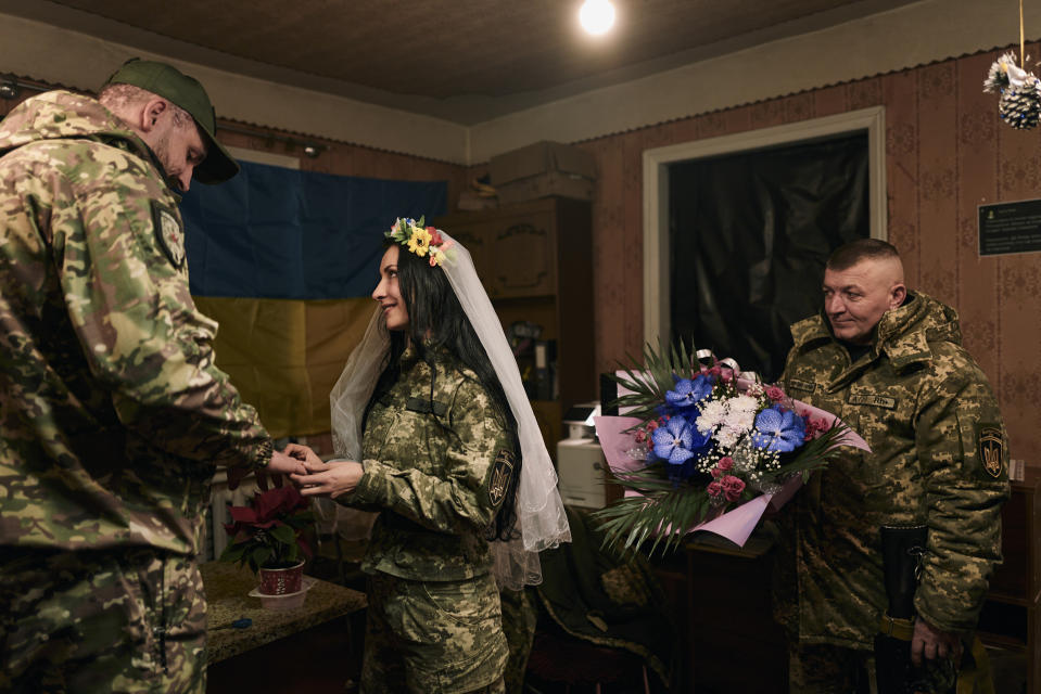 Ukrainian army medics Eugenia and Oleksander, left, exchange rings during their wedding ceremony in Lyman, Donetsk region, Ukraine, Saturday, Dec. 24, 2022. (AP Photo/Libkos)