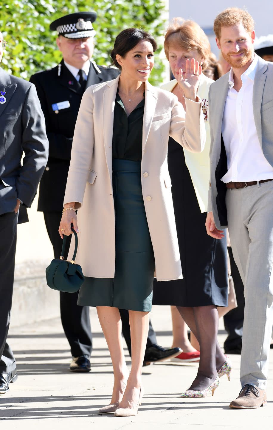 <p>For her inaugural visit to Sussex, Meghan wore a cream-colored Georgia Armani coat over a green leather Hugo Boss skirt and & Other Stories blouse. She also carried a small green top-handled bag.</p>