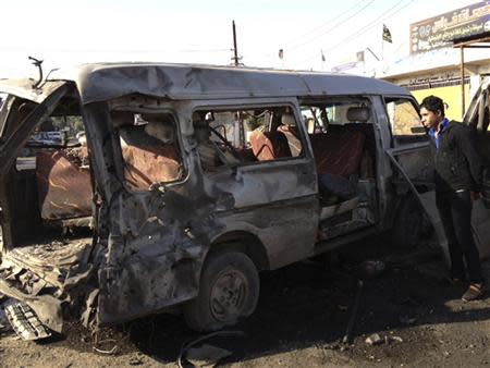 A man looks at a damaged vehicle after a car bomb attack at Bayaa district in Baghdad December 8, 2013. REUTERS/Ahmed Malik