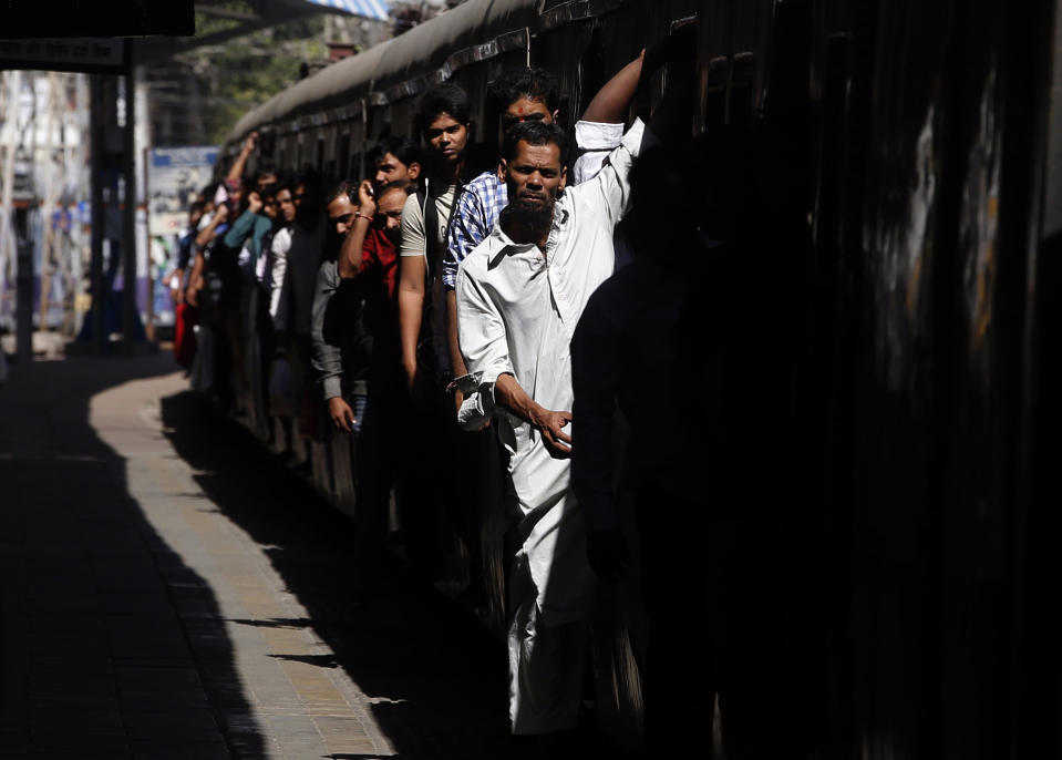 FILE- In this Jan. 22, 2016 file photo, commuters hang out of an overcrowded suburban train as it arrives in Mumbai Central Train Station in Mumbai, India. India's sprawling rail network, the world's third largest, operates more than 12,600 trains carrying passengers and cargo across 115,000 kilometers (71,000 miles) of track. But not all is well with the Indian Railways. For years, it’s been clear that the much-romanticized legacy of British colonial rule, built more than 160 years ago, is badly hobbled by funding shortfalls, aging tracks, outdated signaling and communications systems and a volume of traffic that has pushed these systems beyond their limits. (AP Photo/Rajanish Kakade, File)