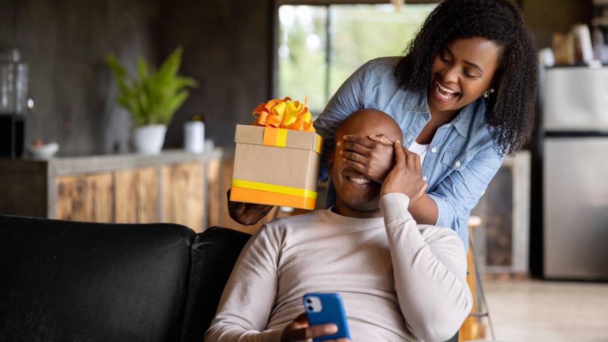 woman at home surprising her husband with a gift