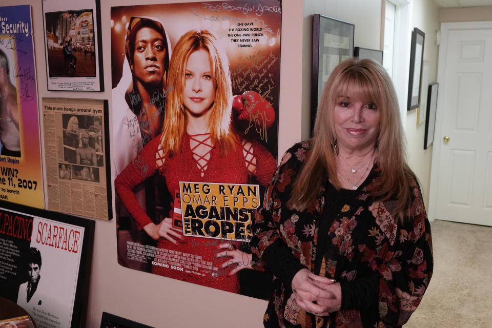 Boxing promoter Jackie Kallen stands next to a poster of the movie Against the Ropes at her home, Friday, May 26, 2023, in West Bloomfield, Mich. The fictional story was inspired by Kallen. The promoter says women in boxing have shown that they can sell out big arenas but they're not compensated as well as men in the same sport. "It's like any other profession where the women still haven't caught up," said Kallen. (AP Photo/Carlos Osorio)