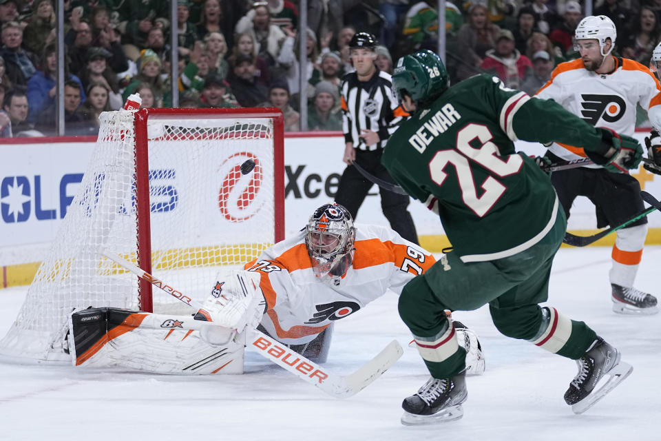 Philadelphia Flyers goaltender Carter Hart (79), left, defends against a shot by Minnesota Wild center Connor Dewar (26) during the first period of an NHL hockey game Thursday, Jan. 26, 2023, in St. Paul, Minn. (AP Photo/Abbie Parr)