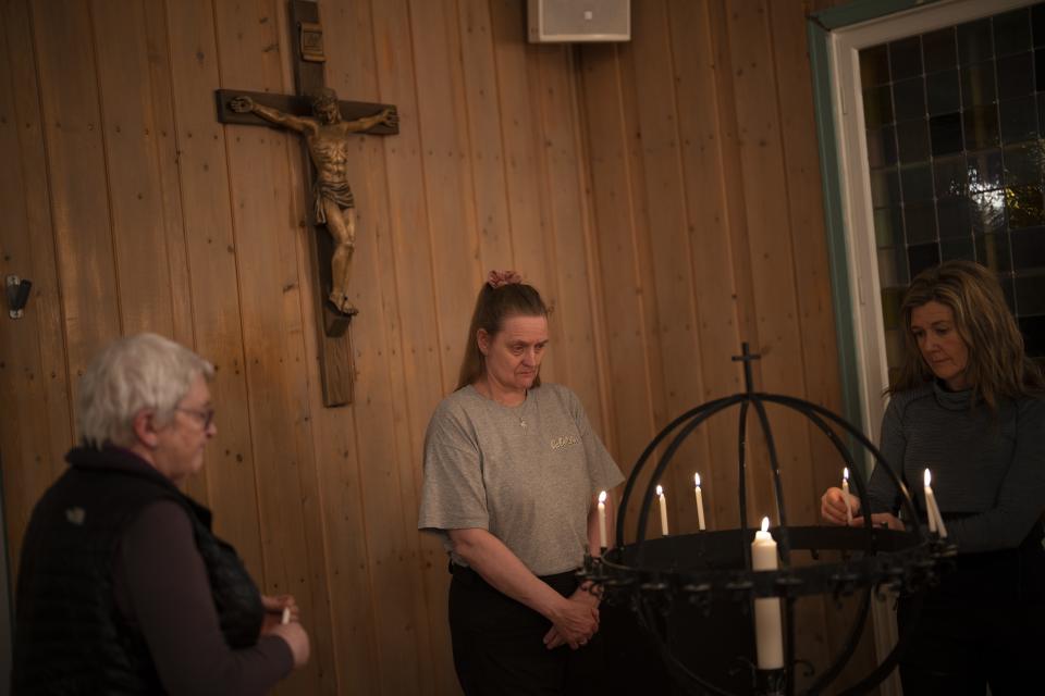 Congregants light candles during evening service at Svalbard Kirke in Longyearbyen, Norway, Tuesday, Jan. 10, 2023. As change swirls faster than the snowdrifts covering Longyearbyen's few miles of paved roads, the church's anchoring role seems poised to remain the only constant. (AP Photo/Daniel Cole)