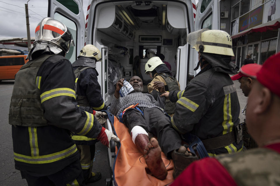 Rescuers carry an injured man into an ambulance after a Russian attack at Barabashovo market in Kharkiv, Ukraine, Thursday, July 21, 2022. (AP Photo/Evgeniy Maloletka)