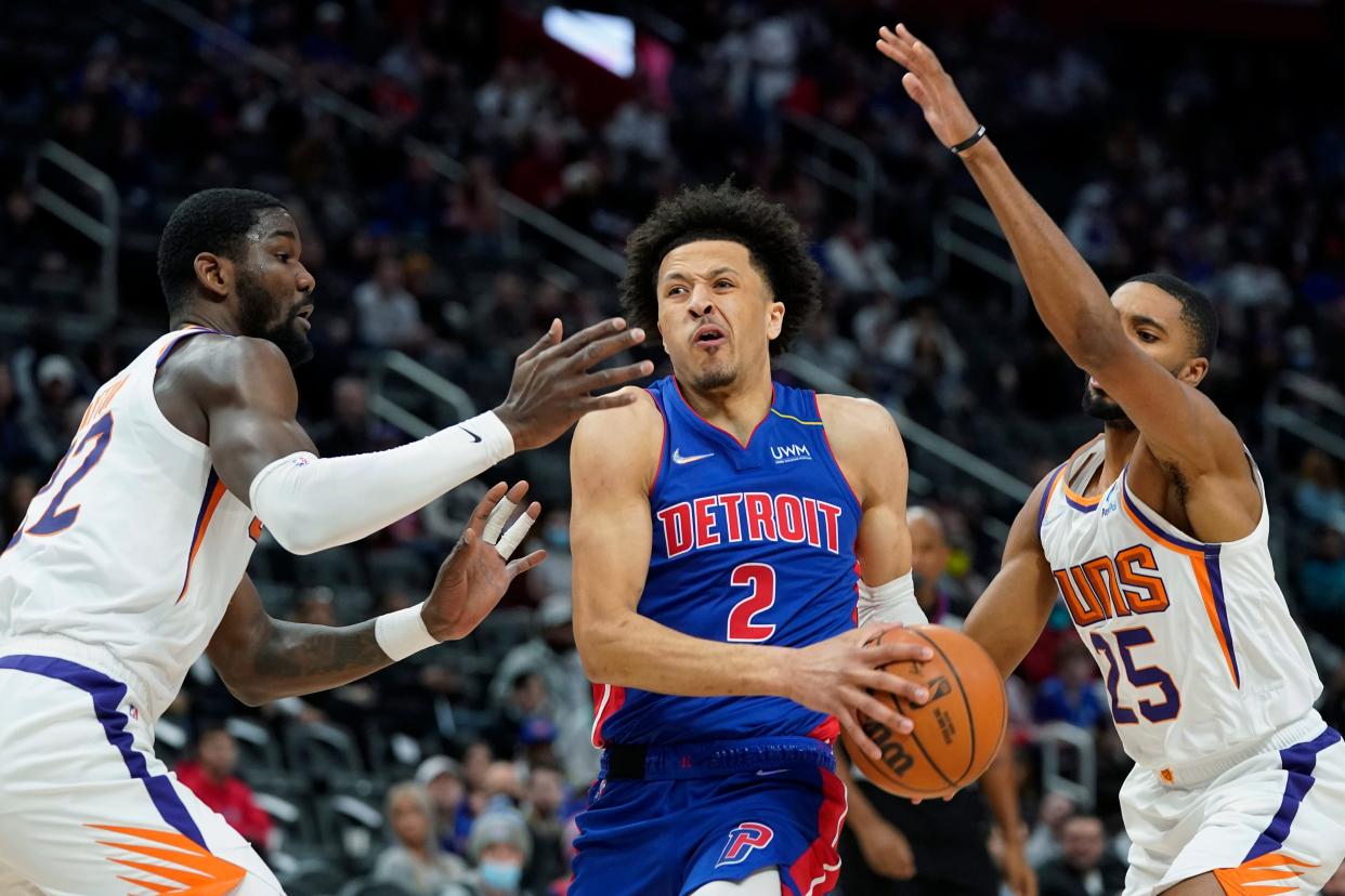 Detroit Pistons guard Cade Cunningham (2) drives to the basket as Phoenix Suns center Deandre Ayton, left, and forward Mikal Bridges (25) defend during the first half of an NBA basketball game, Sunday, Jan. 16, 2022, in Detroit.