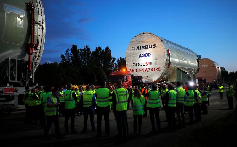 Airbus staff and security members get ready for the departure of a fuselage section of the last Airbus A380 airplane, in the village of L'Isle-Jourdain near Toulouse