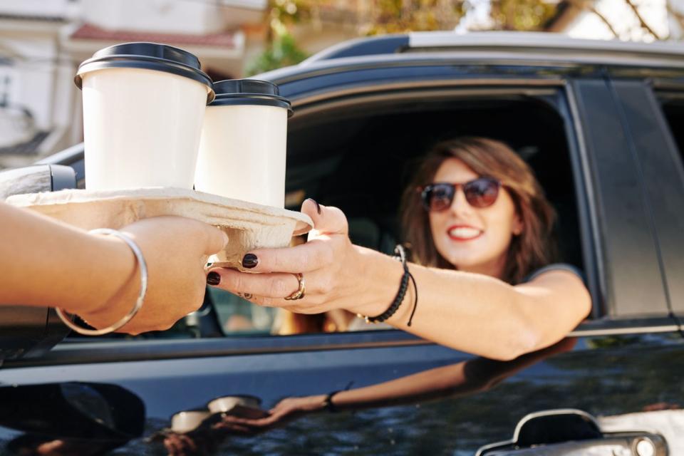 Barista handing coffee to a customer in a drive-thru.
