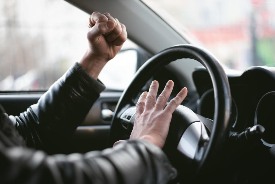 Angry driver is honking and is yelling by sitting of a steering wheel