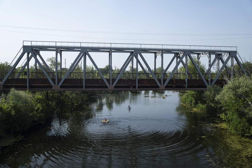 A boy jumps to the water from a bridge on the outskirts of Sloviansk, Ukraine, Monday, June 19, 2023. (AP Photo/Evgeniy Maloletka)