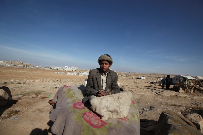 Boy sits in the sun on a cold winter day at a camp for internally displaced people in Khamir of the northwestern province of Amran