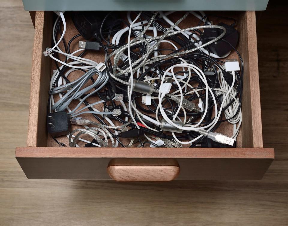 desk drawer filled with cables, wires and plugs