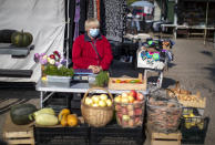 A vegetable vendor wearing a face mask to protect against coronavirus, waits for customers at the bazaar in the small town of Ignalina, some 110km (68.3 miles) north of the capital Vilnius, Lithuania, Saturday, Sept. 26, 2020. (AP Photo/Mindaugas Kulbis)