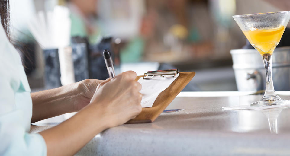 Woman signing receipt after paying bar tab in restaurant