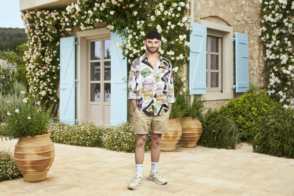 Owen posing in front of a Greek house with blue shutters.