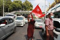 A Buddhist monk waves the flag of deposed Myanmar leader Aung San Suu Kyi's National League for Democracy party in the middle of vehicular traffic in Yangon, Myanmar on Sunday, Feb. 7, 2021. Thousands of people rallied against the military takeover in Myanmar's biggest city on Sunday and demanded the release of Aung San Suu Kyi, whose elected government was toppled by the army that also imposed an internet blackout. (AP Photo)