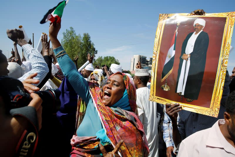 Supporters of Sudanese former president Omar Hassan al-Bashir carry his picture during a protest outside the court house that convicted him on corruption charges in Khartoum