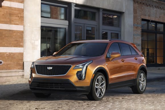 A copper-colored 2019 Cadillac XT4, a compact crossover SUV, parked in front of a commercial building.