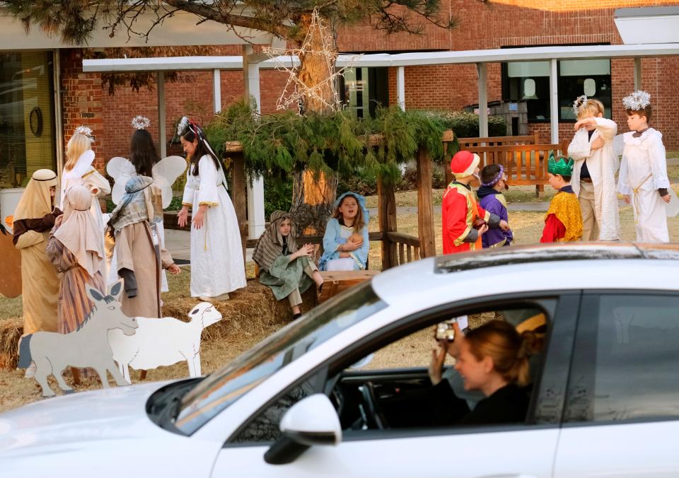 A car slows down to take a photo as students at Casady's Lower Division dressed as biblical characters create a live Nativity scene on Thursday as students are dropped off at the school, 9500 N Pennsylvania.