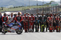 Teammates of 19 years-old Swiss pilot Jason Dupasquier and pilots from other teams stand near his motorbike as they pay a minute of silence in his memory prior to the start of the Motogp Grand Prix of Italy at the Mugello circuit, in Scarperia, Italy, Sunday, May 30, 2021. Dupasquier died Sunday after being hospitalized Saturday, at the Florence hospital following his crash during the qualifying practices of the Moto3. (AP Photo/Antonio Calanni)