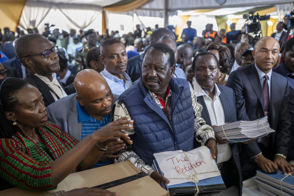 Presidential candidate Raila Odinga, center, hands over the petition to the Supreme Court challenging the election results, accompanied by running mate Martha Karua, left, in Nairobi, Kenya Monday, Aug. 22, 2022. Kenya's losing presidential candidate Odinga filed the Supreme Court challenge to last week's election results Monday, starting the 14-day period in which the court must rule. (AP Photo/Ben Curtis)
