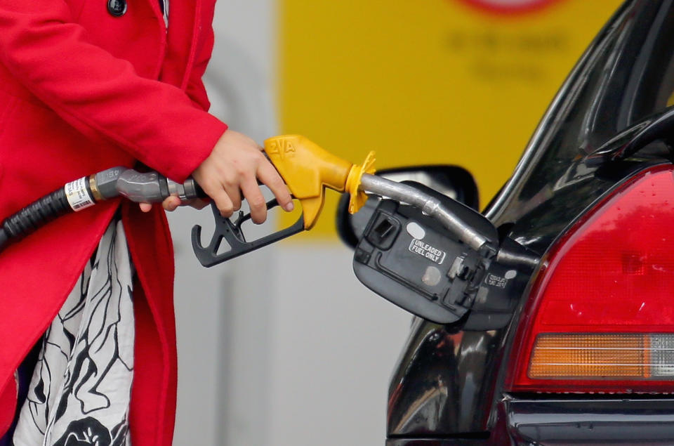 A woman uses a fuel dispenser to fill her car up. (Source: Getty)