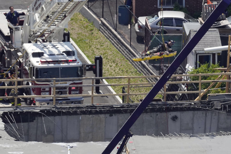 Firefighters rescue a worker after the partial collapse of a building under construction, Friday, June 2, 2023, in New Haven, Conn. The building, near the Yale School of Medicine, partially collapsed when a concrete pour went awry, foreground, injuring eight people including two critically, city officials said, adding there were no fatalities. (Paul Haring via AP)