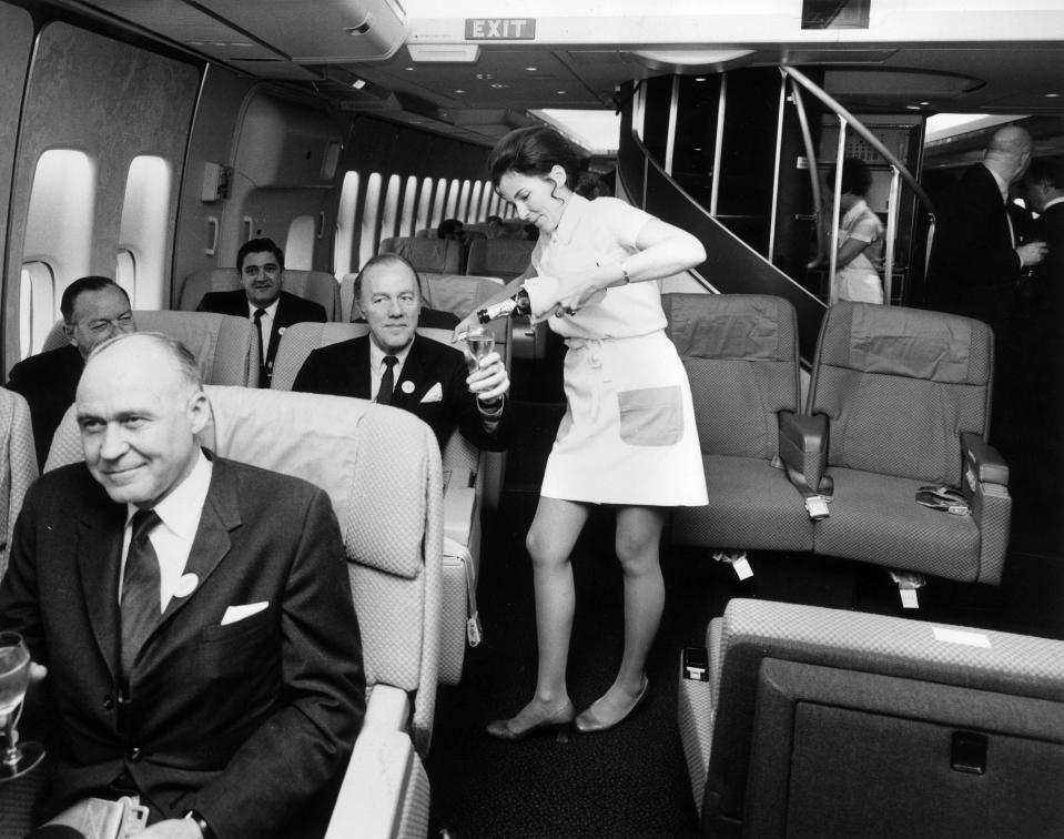 A flight attendant serves Champagne to first-class passengers on a Boeing 747.