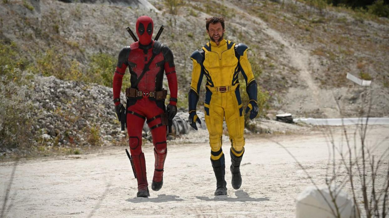  Deadpool and Wolverine walk down a dirt road in their classic comic book costumes in Deadpool 3. 