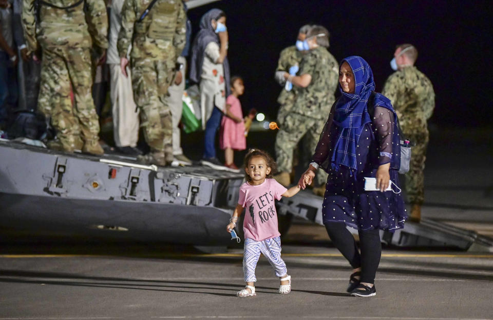 CORRECTS PHOTOGRAPHER TO DANIEL YOUNG - Evacuees from Afghanistan disembark from a U.S. Air Force C-17 Globemaster III at the Sigonella US air base, in Sicily, southern Italy, Sunday, Aug. 22, 2021. People fleeing Afghanistan arrived at the U.S. naval air base in Sicily as Washington tried to ramp up evacuations following the Taliban takeover of the country by using overseas military bases as temporary transit points. (Daniel Young/U.S. Navy via AP)