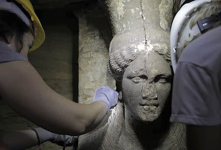 Archaeologists work on a sculpted female figure, known as Caryatid, inside a site of an archaeological excavation at the town of Amphipolis, in northern Greece, in this handout photo taken September 6, 2014, and distributed by Greece's Culture ministry. REUTERS/Hellenic Culture Ministry/Handoutb via Reuters