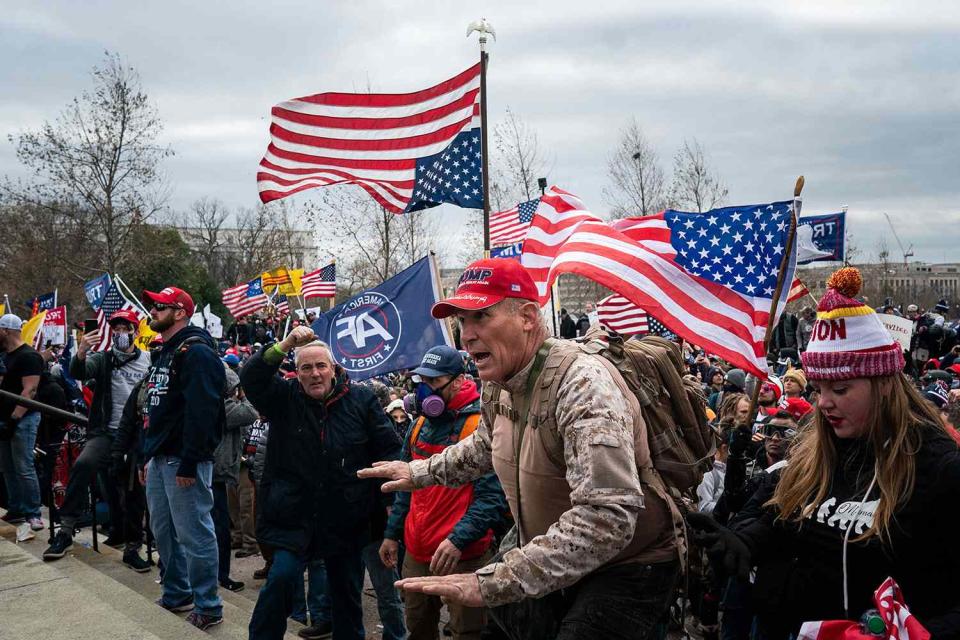 <p>Kent Nishimura / Los Angeles Times via Getty</p> Ray Epps, in the red Trump hat, center, gestures to a line of law enforcement officers, as people gather on the West Front of the U.S. Capitol on Jan. 6, 2021