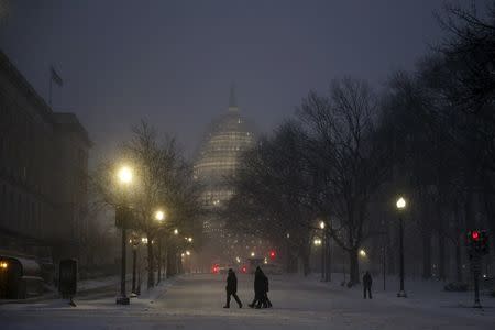 People walk in the falling snow near the U.S. Capitol in Washington January 22, 2016. REUTERS/Jonathan Ernst