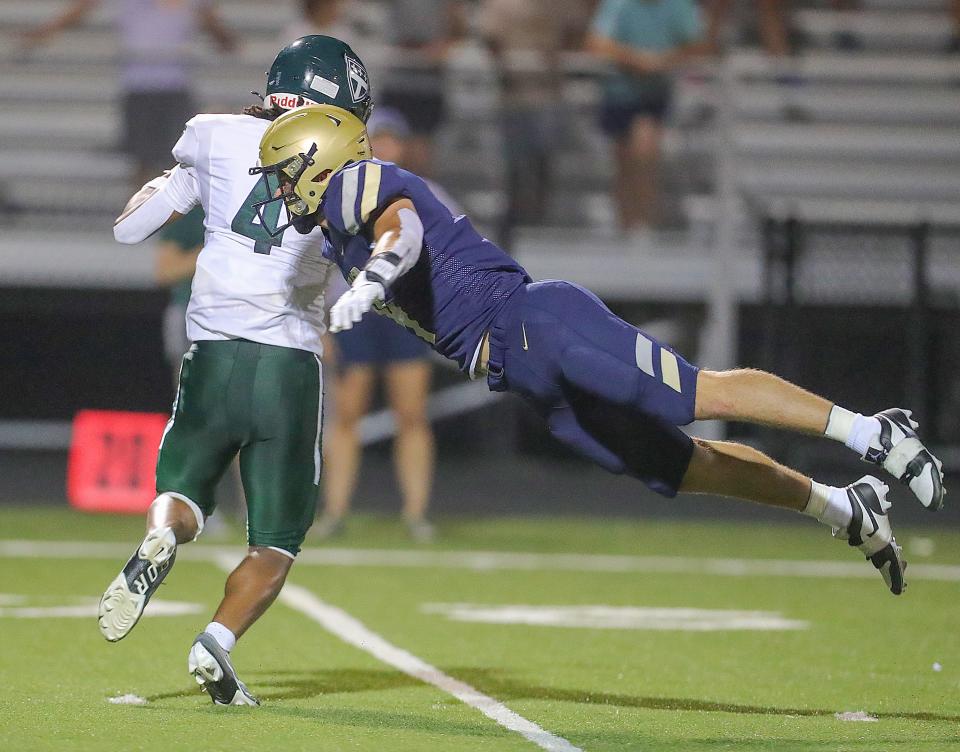 Hoban linebacker Tanner Mintz makes a diving tackle on Trinity Episcopal School's Davion Brown on Sept. 2.
