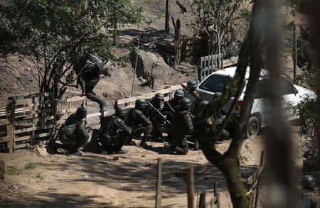 Brazilian Army soldiers take cover during a shootout with drug gangs during an operation in Alemao slums complex in Rio de Janeiro, Brazil August 20, 2018. REUTERS/Ricardo Moraes