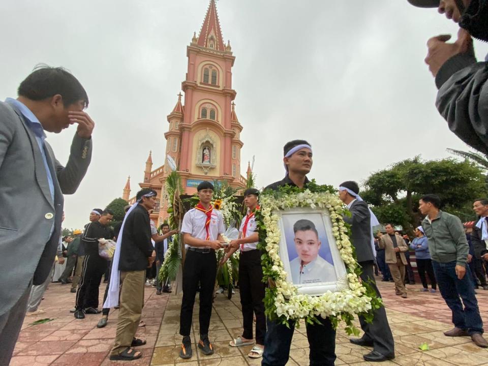 The brother of Hoang Van Tiep carries his portrait outside Trung Song church during his funeral on Thursday, Nov. 28, 2019, in Dien Chau, Vietnam. The 18-year old Tiep was among the 39 Vietnamese who died when human traffickers carried them by truck to England in October, and whose remains were among the 16 repatriated to their homeland Wednesday. (AP Photo/Hau Dinh)
