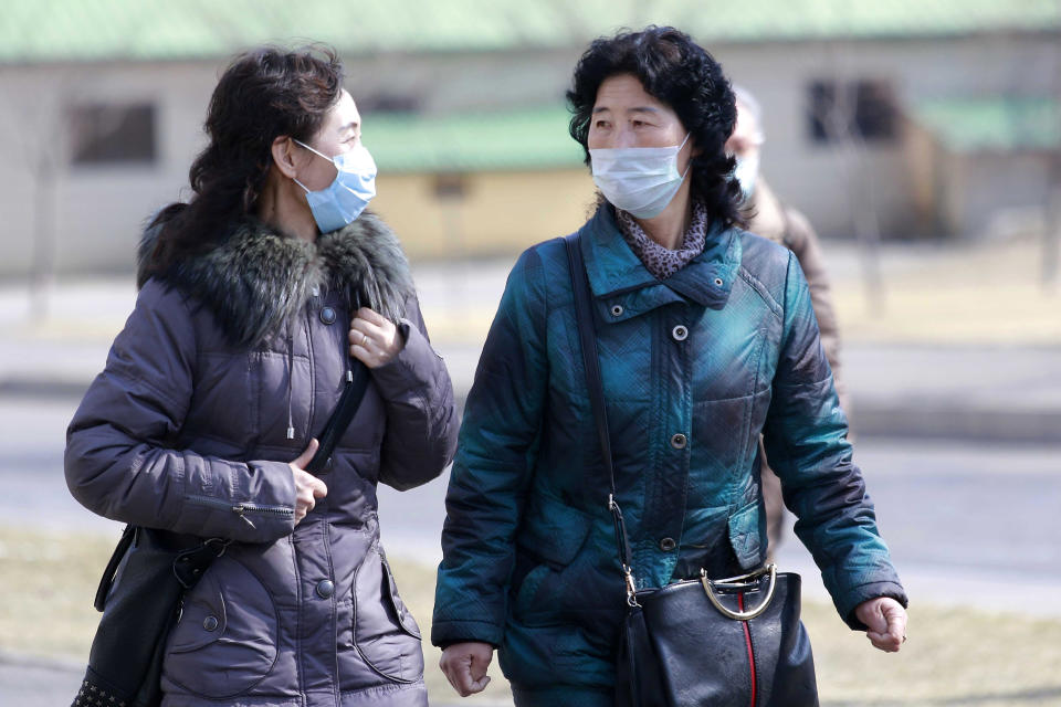 FILE - In this Feb. 26, 2020 file photo, people wear masks to protect from a new coronavirus as they walk through the Kwangbok Street in Pyongyang, North Korea. As a new and frightening virus closes in around it, North Korea presents itself as a fortress, tightening its borders as cadres of health officials stage a monumental disinfection and monitoring program. (AP Photo/Jon Chol Jin, File)