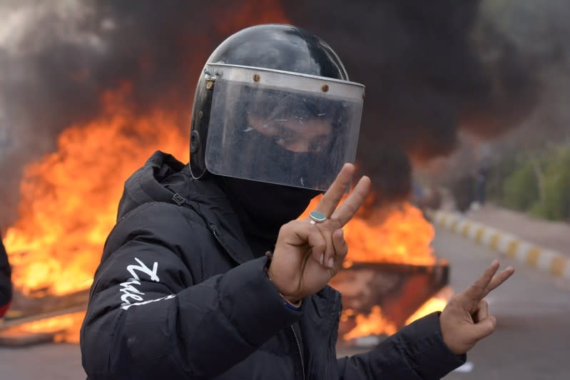 A demonstrator wearing a helmet poses for a photograph during ongoing anti-government protests in Nassiriya