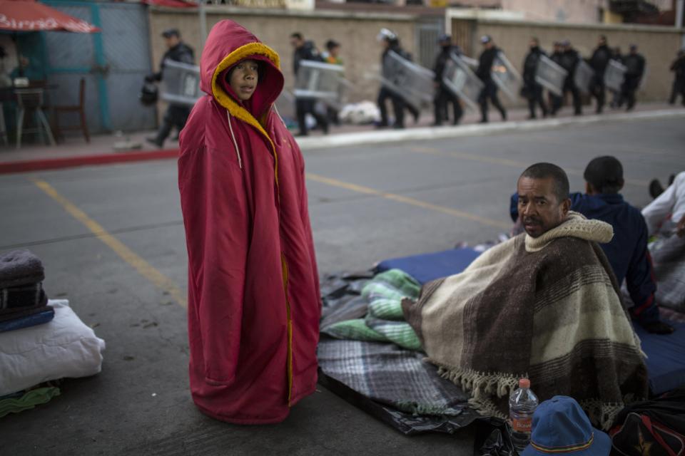 Jonathan Torres, 11, stands next to his father after waking up early in the morning as Mexican riot police make their way to the Chaparral border crossing, in Tijuana, Mexico, Friday, Nov. 23, 2018. The mayor of Tijuana has declared a humanitarian crisis in his border city and says that he has asked the United Nations for aid to deal with the approximately 5,000 Central American migrants who have arrived in the city.(AP Photo/Rodrigo Abd)