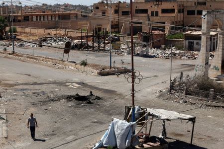 A man walks near a hole in the ground after an airstrike on Sunday in the rebel-held town of Dael, in Deraa Governorate, Syria September 19, 2016. REUTERS/Alaa Al-Faqir